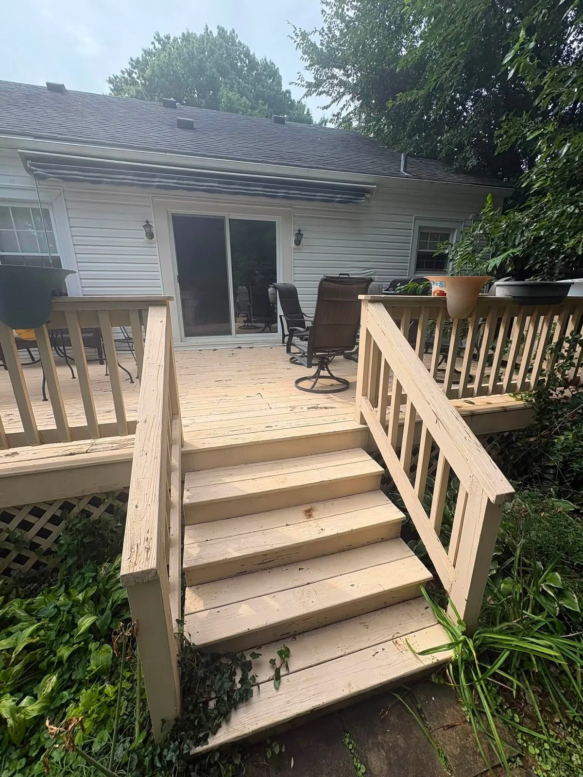 After: cream-colored wood deck, steps and railings leading to a sliding door, with patio chairs on the deck