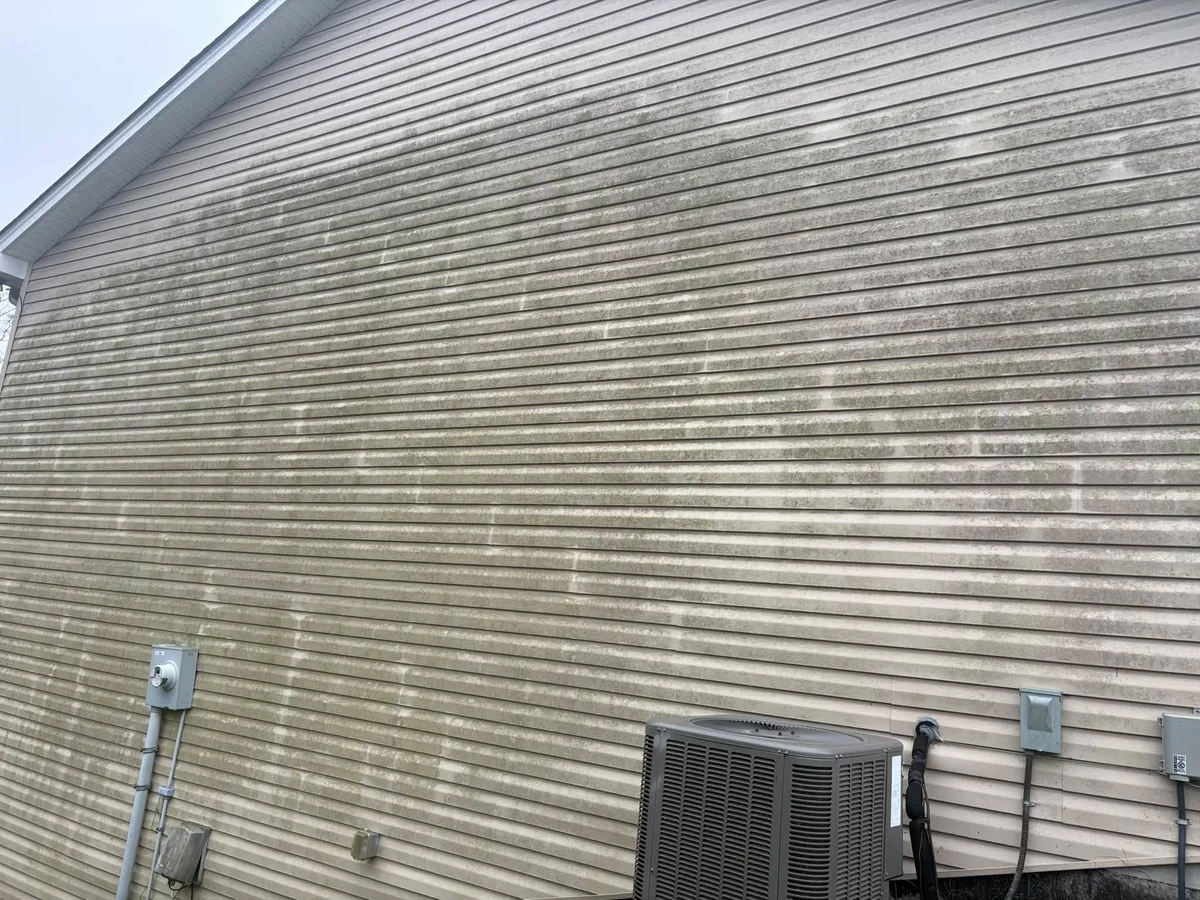 Before: tan vinyl siding with green and gray streaks, with an air conditioner unit and electric meter at the base